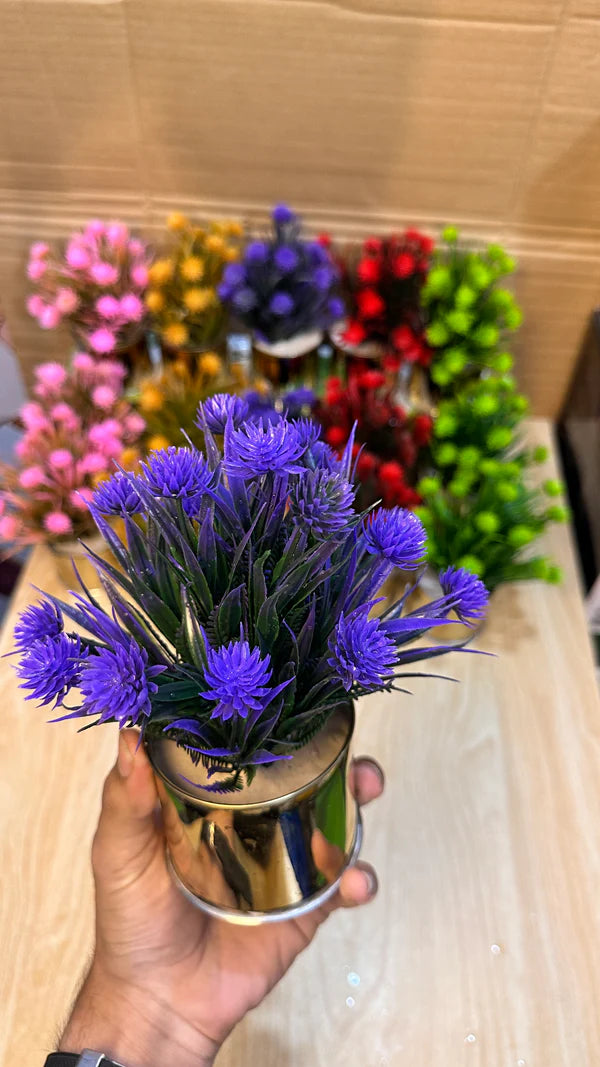 Small potted plant with blue flowers held by a hand against a colorful background.
