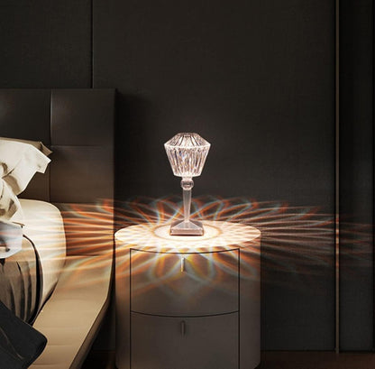 Decorative crystal lamp on a nightstand with a dark wall and bed in the background