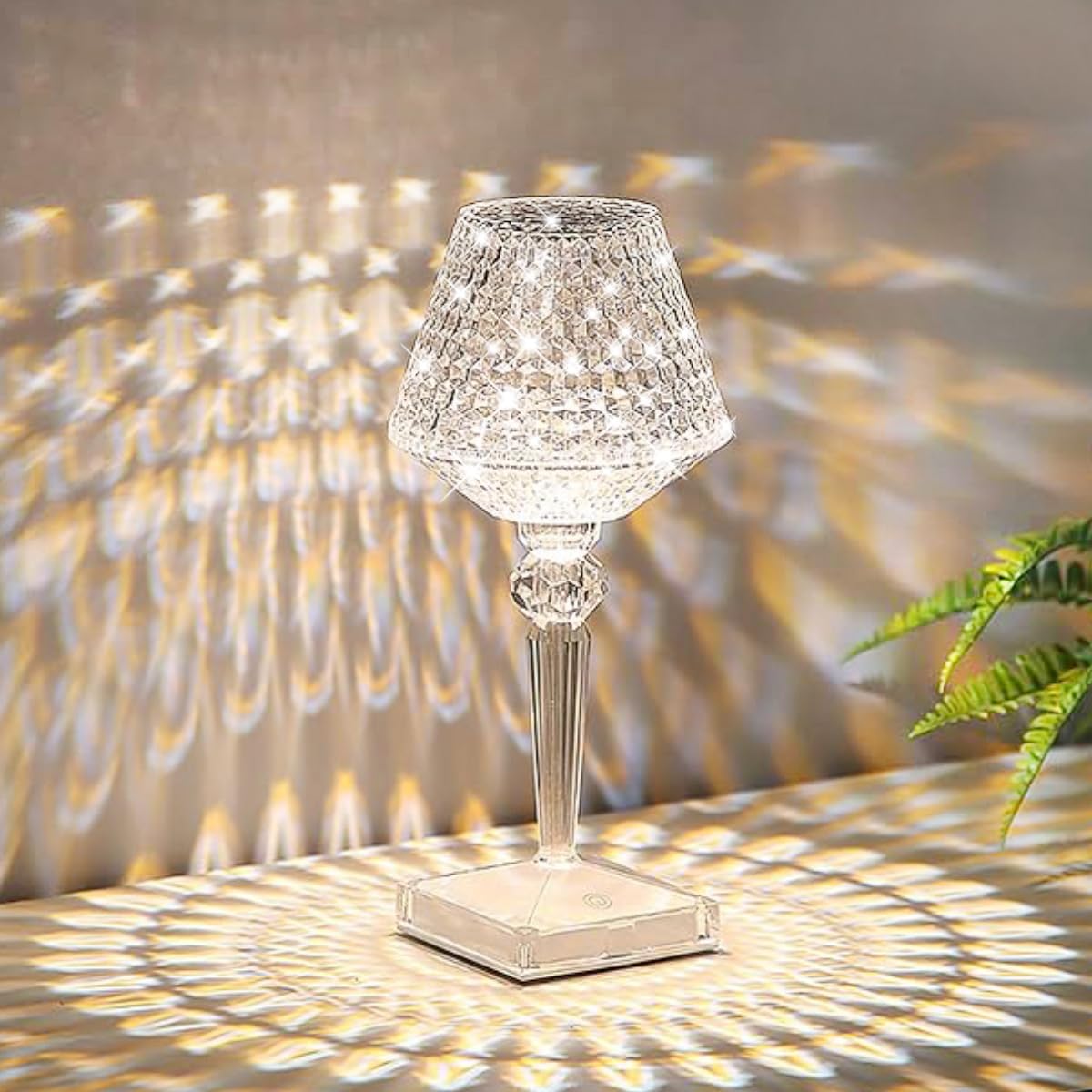 Crystal table lamp casting a pattern on a wall with a plant in the corner.