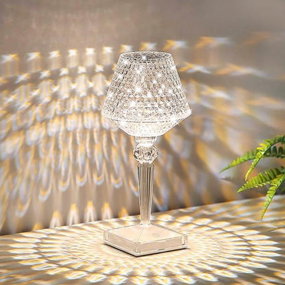 Crystal table lamp casting a pattern on a wall with a plant in the corner.