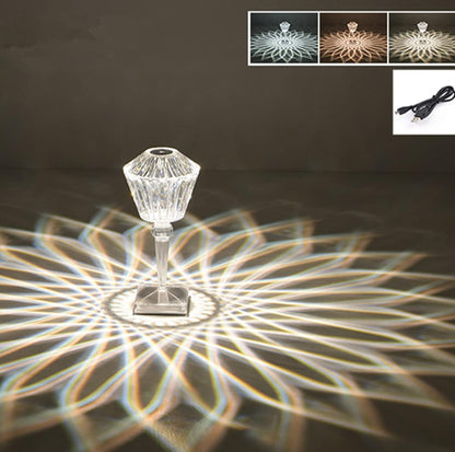 Decorative lamp with crystal design casting a floral pattern on a dark surface, with inset images and a power cord.