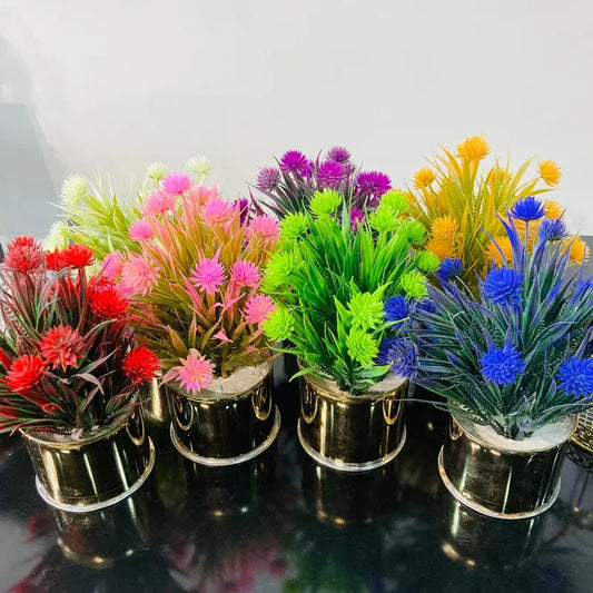 Set of colorful artificial plants in small pots on a reflective surface.